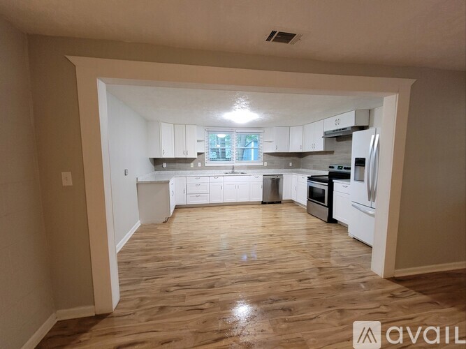 A kitchen with white appliances and wooden floors.
