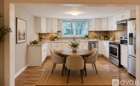 A kitchen with white cabinets and a round table with chairs.