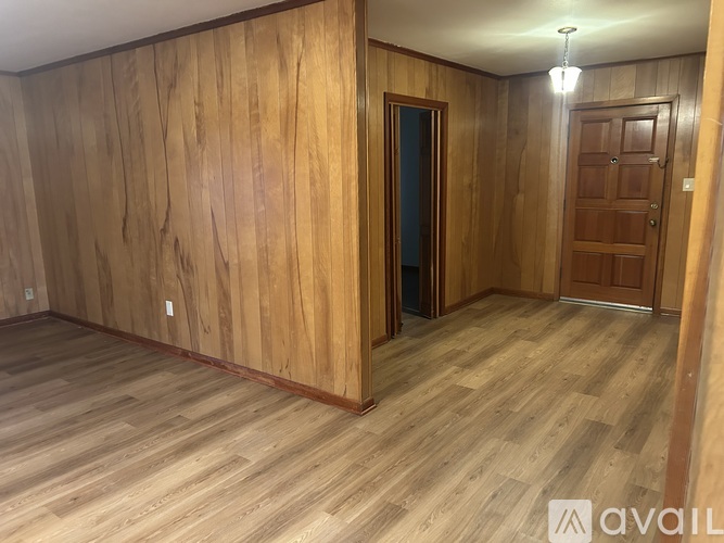 A room with wooden walls and floors, and two doors.