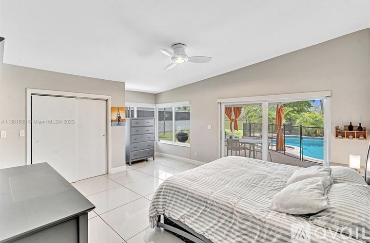A bedroom with a large bed and a pool outside the window.