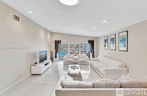 A modern living room with a large white sofa and a flat screen TV.