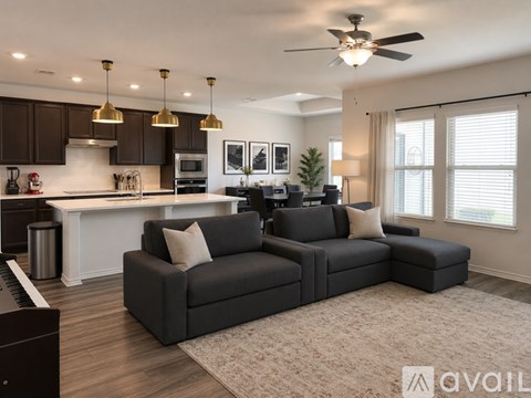 A modern living room with a grey sofa and a kitchen area in the background.