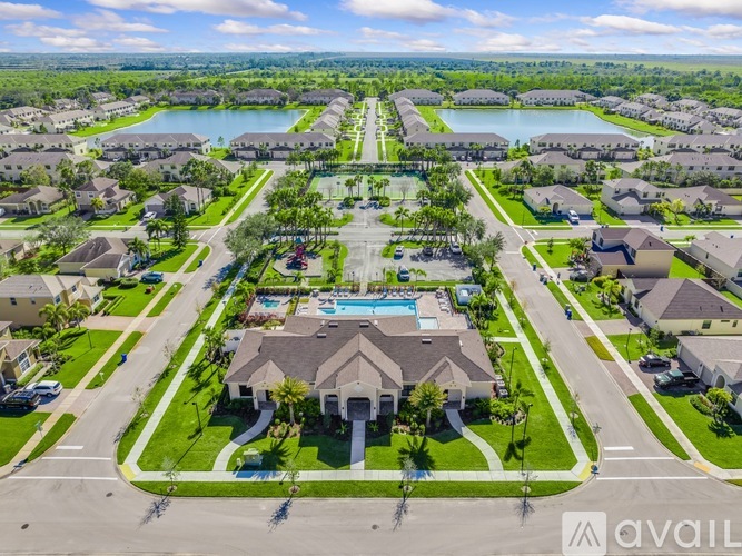 A bird's eye view of a residential area with a swimming pool and a lake in the background.