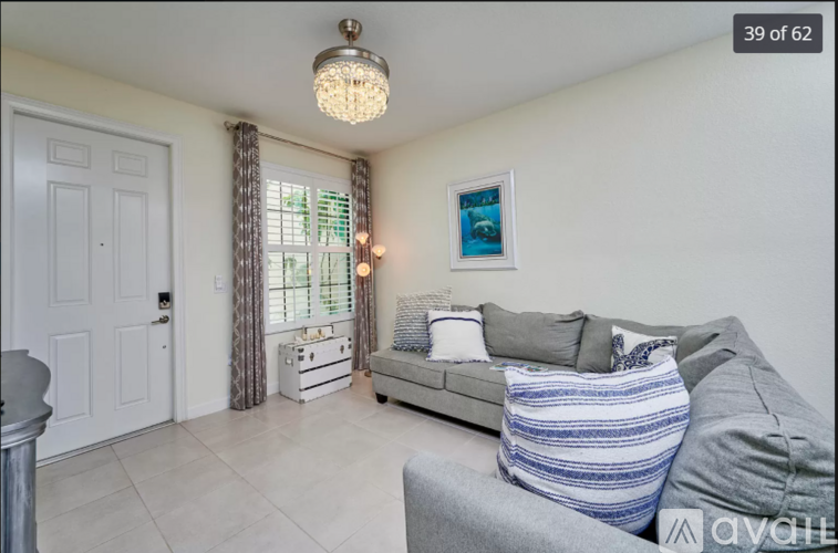 A living room with a grey couch and a chandelier.