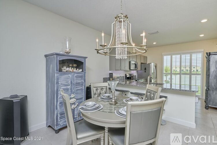 A dining room with a chandelier, a dining table with chairs, and a cabinet.