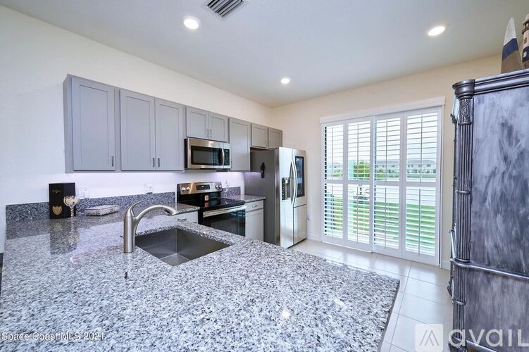 A kitchen with granite countertops and a refrigerator with a water dispenser.