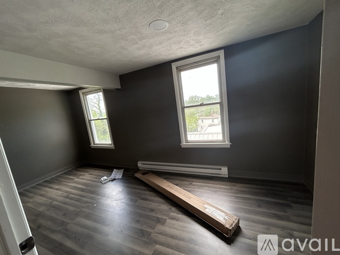 A room with dark walls and a wooden plank on the floor.