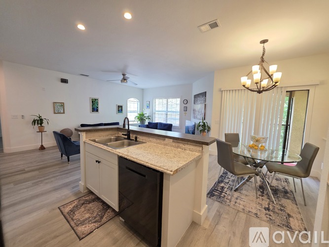 A kitchen with a sink, a dining table and chairs, and a ceiling fan.