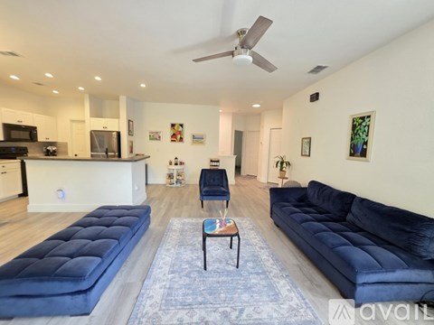 A living room with a blue couch and a ceiling fan.