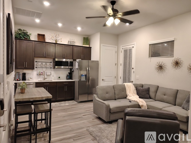 A modern kitchen with a dining table and a grey couch.