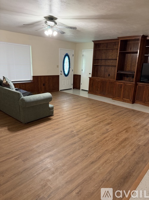 A living room with a grey couch and wooden floors.