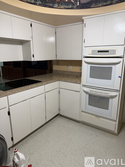 A kitchen with white cabinets and a white oven.