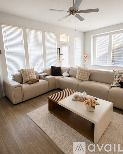 A living room with a beige sofa, a coffee table, and a ceiling fan.