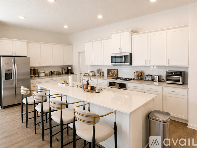 A kitchen with white cabinets and a white island with bar stools.
