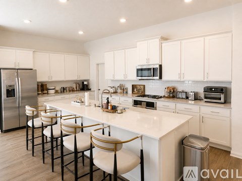 A kitchen with white cabinets and a white island with bar stools.
