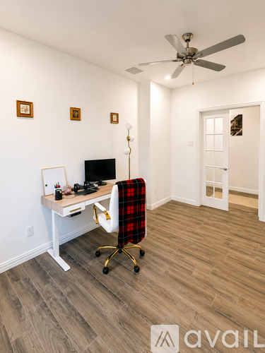 A room with a desk, chair, and a fan.