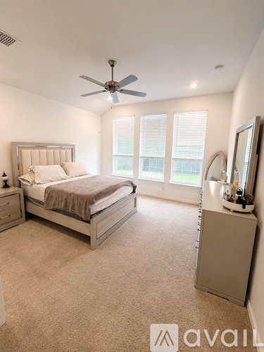 A bedroom with a bed, nightstand, and a fan.