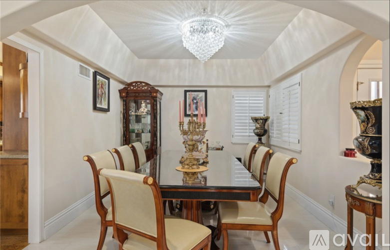 A dining room with a chandelier, a table with chairs, and a cabinet.