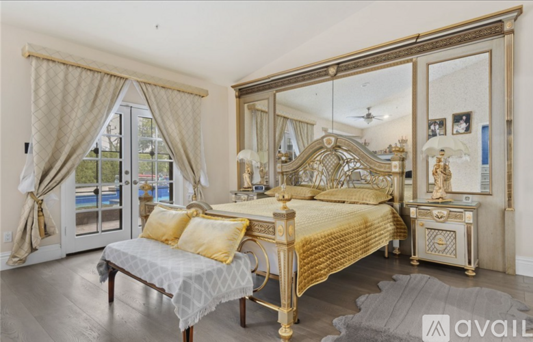 A bedroom with a large bed, a bench, and a dresser with a mirror above it.