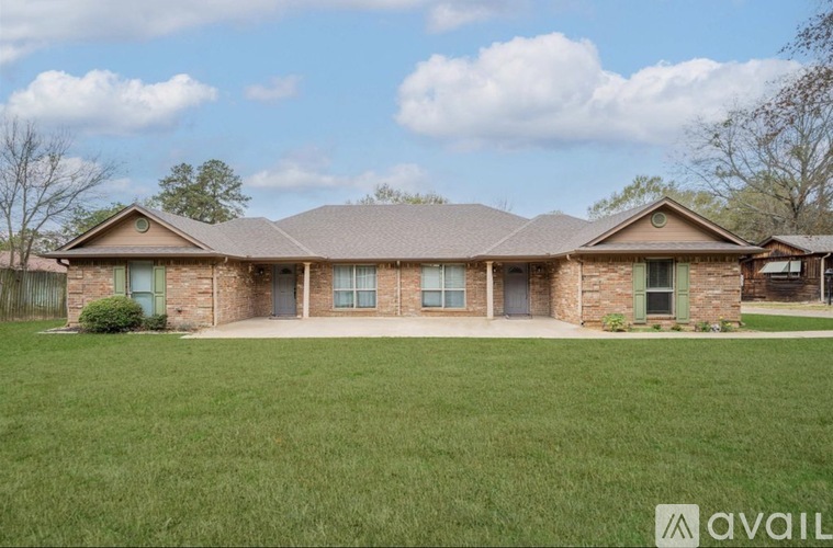 A house with a brown roof and a green lawn in front.