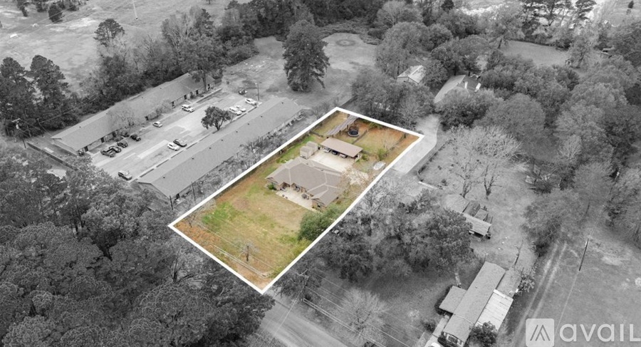 An aerial view of a property surrounded by trees and a parking lot.