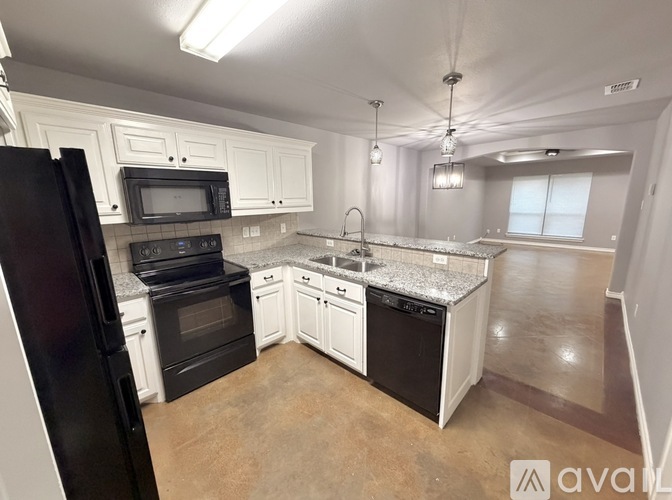 A kitchen with black appliances and white cabinets.
