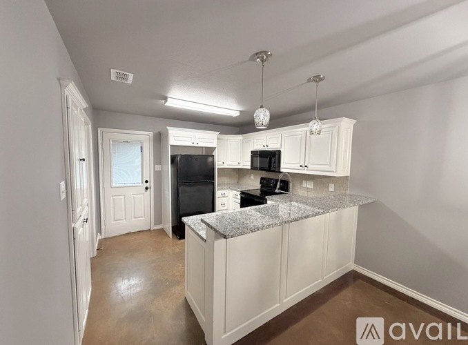 A kitchen with white cabinets and a granite countertop.