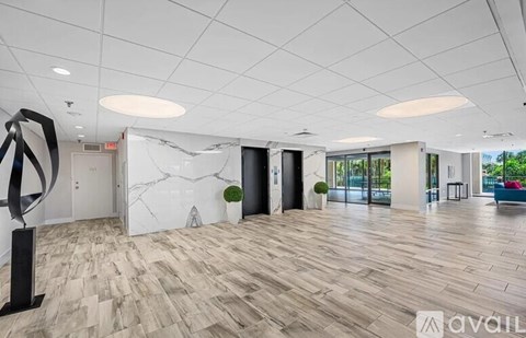 A spacious office lobby with a marble wall and wooden flooring.