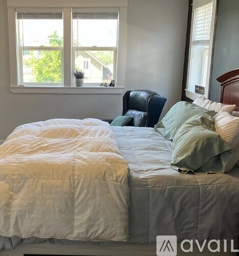 A bedroom with a bed and a chair by the window.