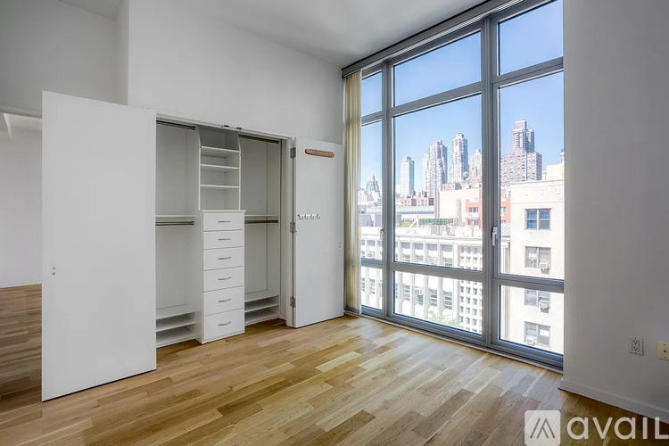 A room with a wooden floor and a large window overlooking a cityscape.