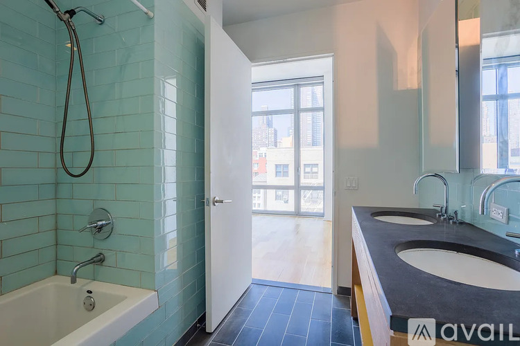 A bathroom with a blue tiled shower and a white bathtub.