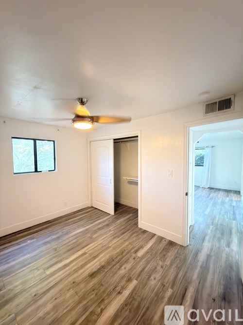 A room with a ceiling fan and wooden flooring.