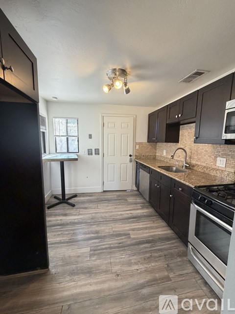 A kitchen with black cabinets and a wooden floor.