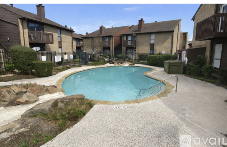 A small pool surrounded by a gravel area and residential buildings.