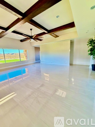 A spacious room with a ceiling fan and large windows.