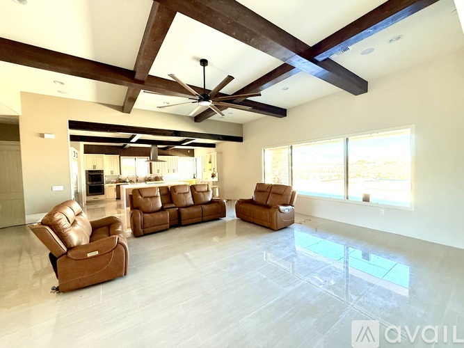 A living room with brown leather furniture and a ceiling fan.