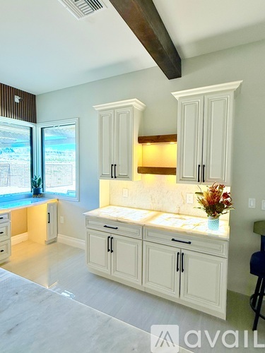 A kitchen with white cabinets and a marble countertop.