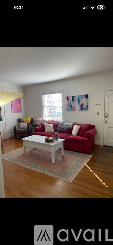 A living room with a red couch and a white coffee table.
