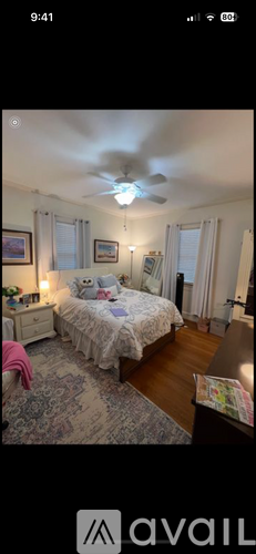 A bedroom with a bed, dresser, and ceiling fan.