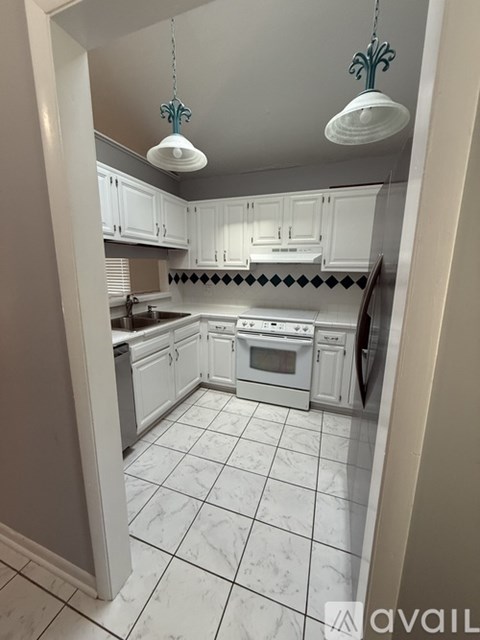 A kitchen with white cabinets and a tiled floor.