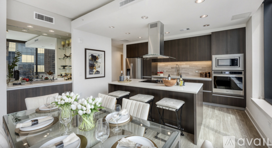 A modern kitchen with a glass dining table set for two.