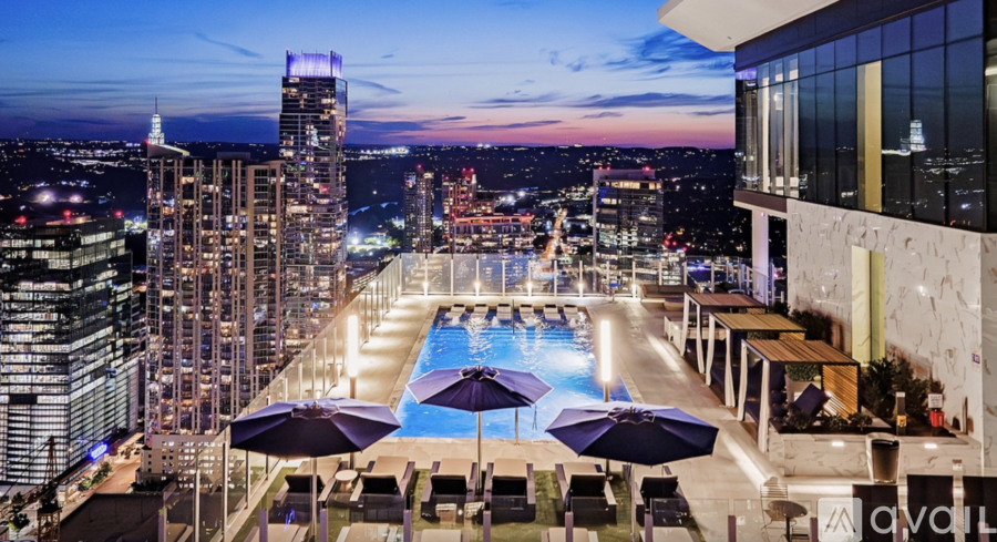 A rooftop pool area with a city skyline at dusk.