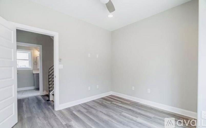 A spacious room with a wooden floor and a staircase leading to another room.