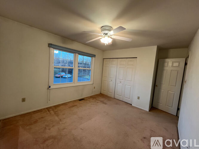 A room with a ceiling fan and a window overlooking a pool.