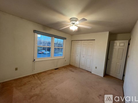 A room with a ceiling fan and a window overlooking a pool.