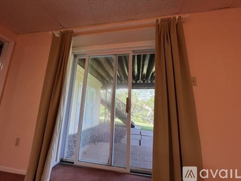 A room with a sliding glass door and brown curtains.