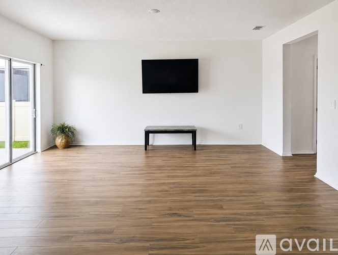 A living room with a bench and a flat screen TV mounted on the wall.