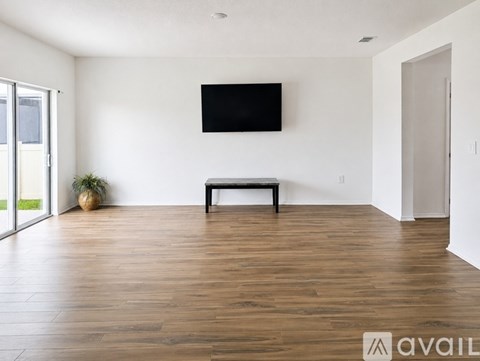 A living room with a bench and a flat screen TV mounted on the wall.