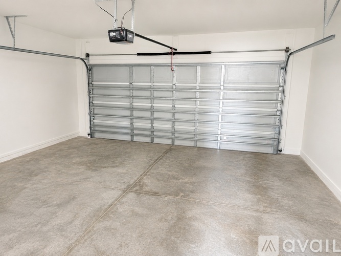 A spacious garage with a closed metal door and a hanging light fixture.