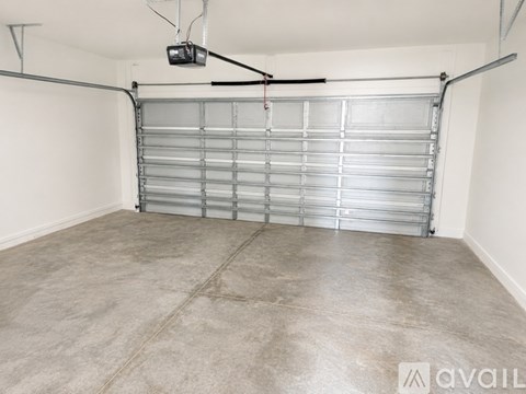 A spacious garage with a closed metal door and a hanging light fixture.